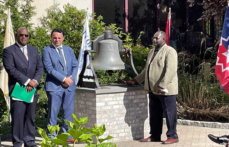 Historian Jimmy Richardson rings the Freedom Bell on Tuesday. Mayor Andre Sayegh and Dwayne Cox, president of the Paterson Parking Authority, look on.